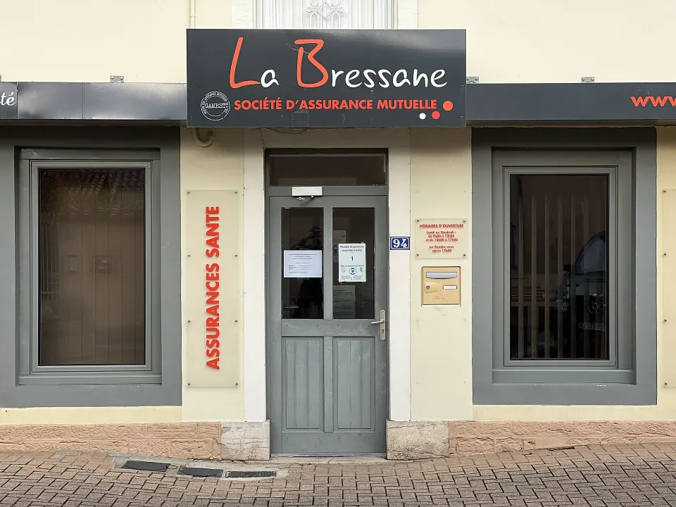Devanture d'une mutuelle d'assurance à Bâgé-le-Châtel, dans l'Ain : enseigne « La Bressane », porte grise entre deux vitrines