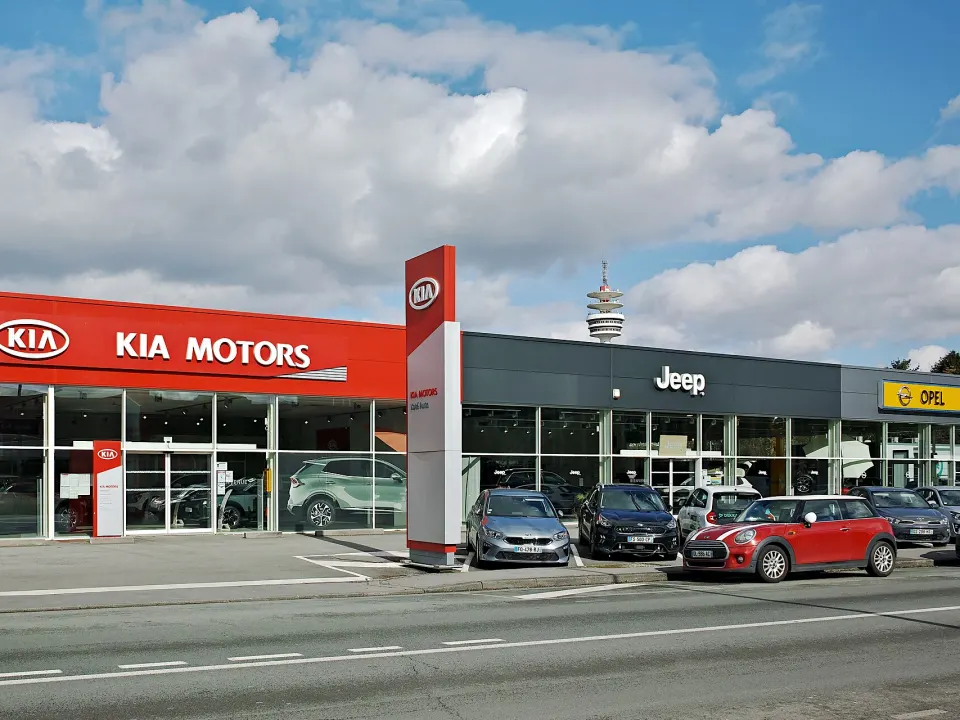 Concessions automobiles rue Jules-Guesde à Villeneuve-d'Ascq, dans le Nord : vitrines Kia, Jeep et Opel, des voitures garées devant
